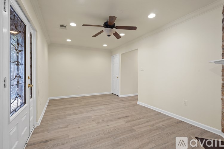 A room with a ceiling fan and wooden flooring.