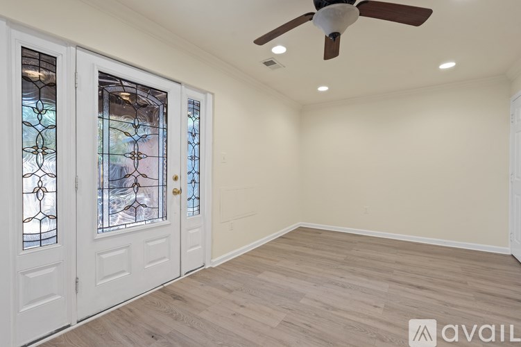 A room with a ceiling fan and a door with a glass window.