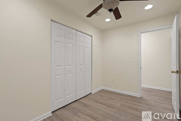 A room with a white door and a ceiling fan.