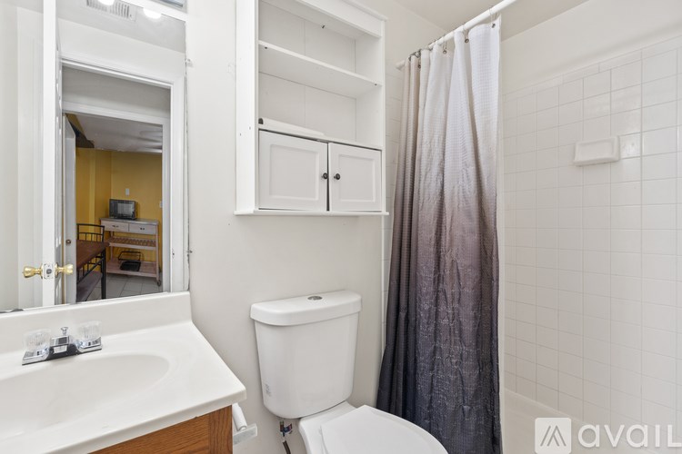 A bathroom with a white toilet, sink, and shower.