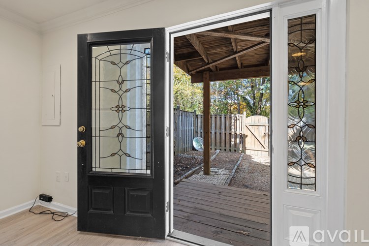 A black door with a glass window and a wooden deck outside.