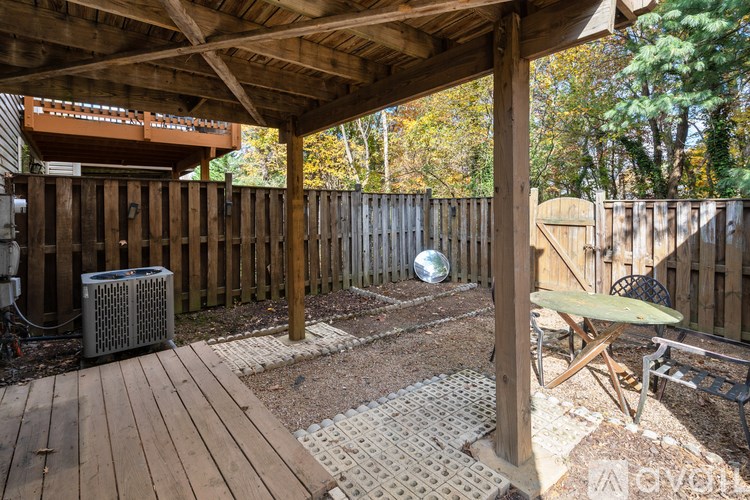 A wooden deck with a table and chairs and a surfboard leaning against a fence.