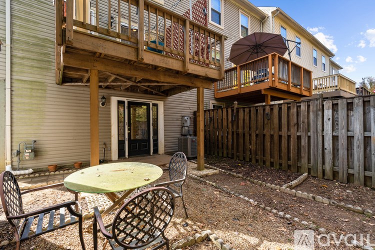 A patio with a table and chairs is in front of a house.