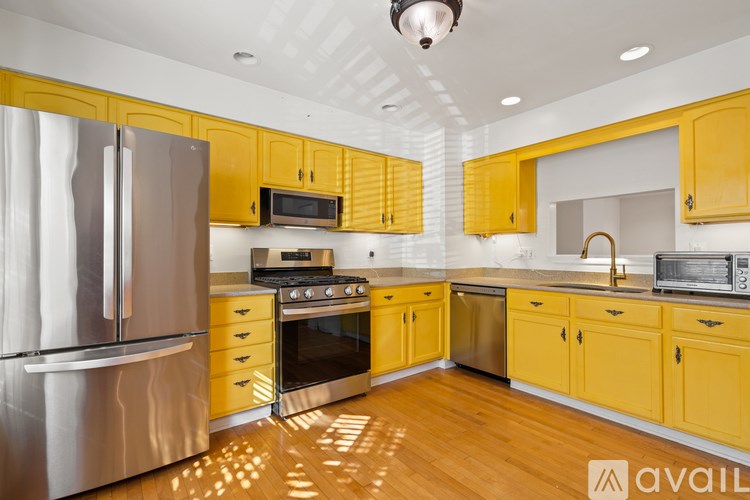 A kitchen with yellow cabinets and stainless steel appliances.