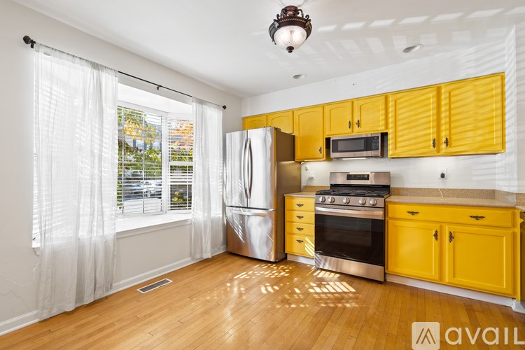 A kitchen with yellow cabinets and a stainless steel refrigerator.
