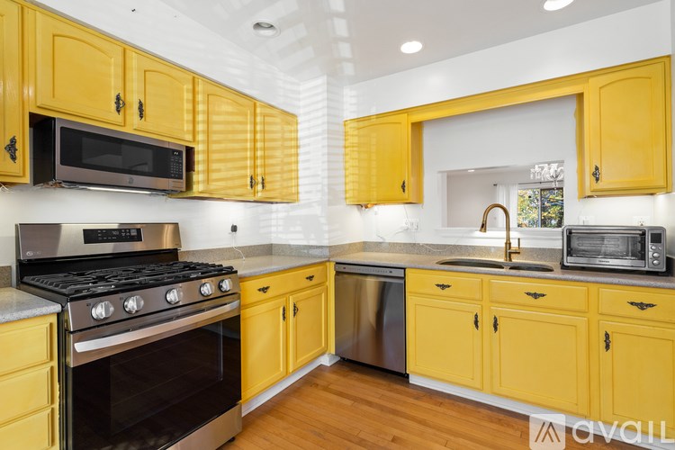 A kitchen with yellow cabinets and a stainless steel dishwasher.
