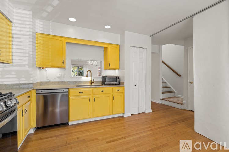 A kitchen with yellow cabinets and a stainless steel dishwasher.