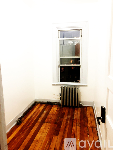 A room with a window and a radiator on the floor.