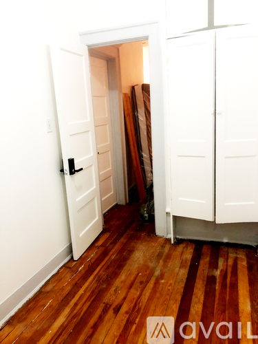 A room with a white door and wooden floor.