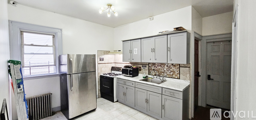 A kitchen with a refrigerator, sink, and cabinets.