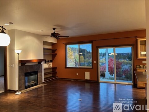 A living room with a fireplace and a painting of a tree.