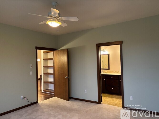 A room with a ceiling fan and a doorway leading to another room.