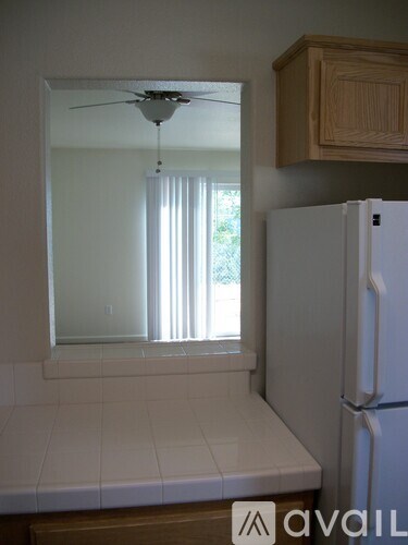 A white fridge in a kitchen with a mirror above the counter.