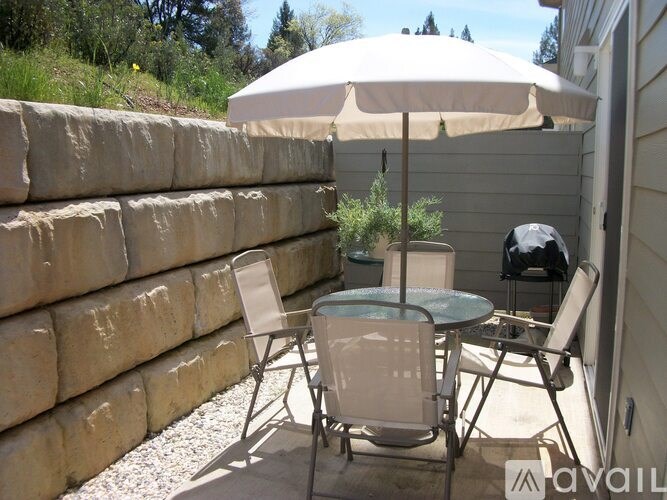 A patio with a table, chairs and an umbrella.