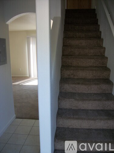 A staircase with a carpeted runner and a white wall.