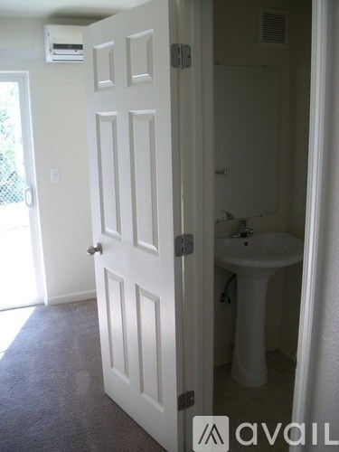 A white door is open to a bathroom with a white sink.