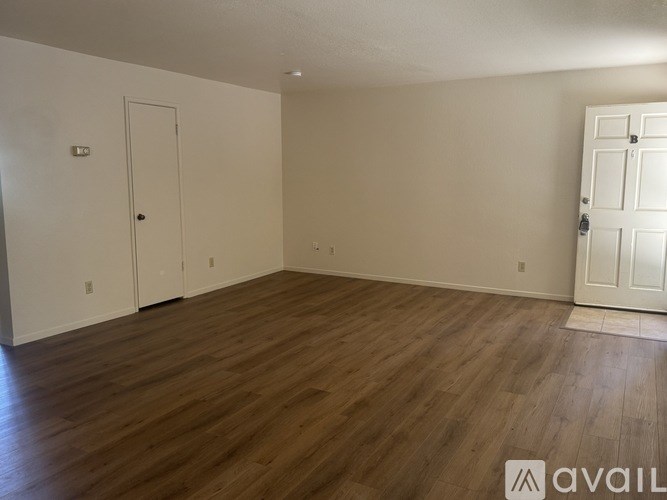 A room with wooden flooring and two doors.