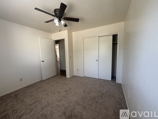 A room with a ceiling fan and carpeted floor.