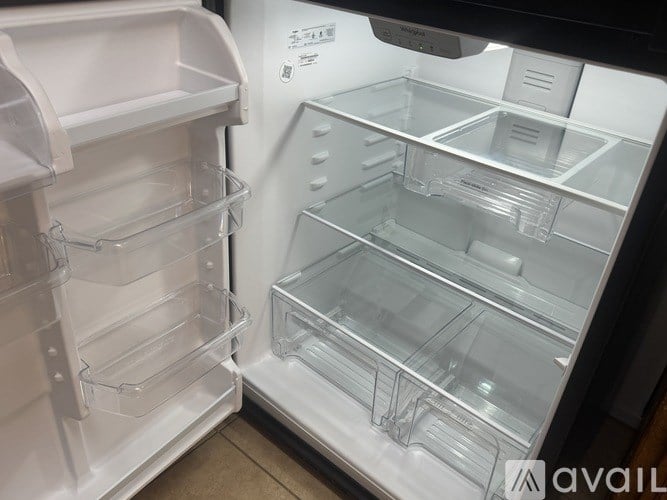 A white refrigerator with its door open showing the empty shelves.