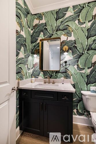 A bathroom with a black cabinet and a mirror above a sink.