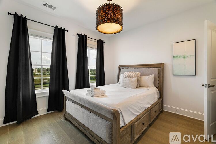A bedroom with a large bed and a window with black curtains.