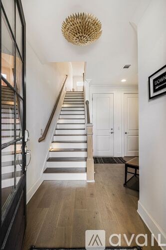A staircase with a wooden handrail and a light fixture above it.