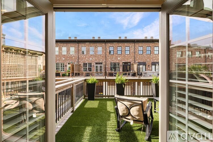 A balcony with a green lawn and two chairs.