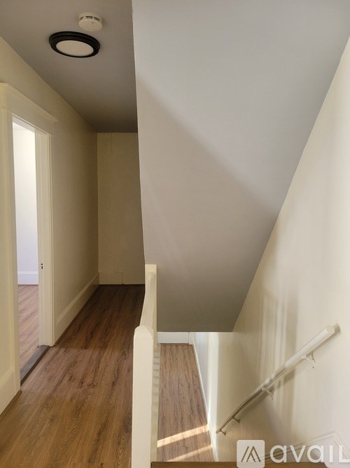 A hallway with a wooden floor and white walls.