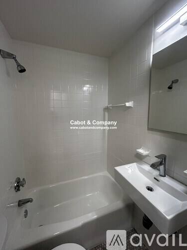 A white bathroom with a tub, sink, and mirror.