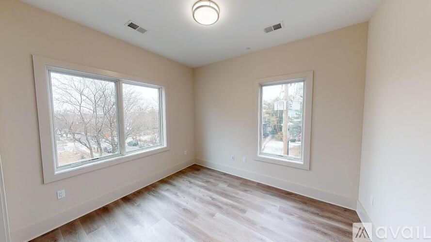 A room with two windows and wooden flooring is available for rent.