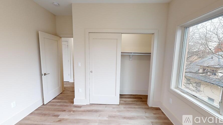 A room with white doors and a window showing a view of a residential area.