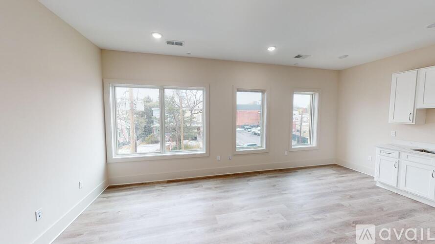 A spacious room with wooden flooring and large windows.