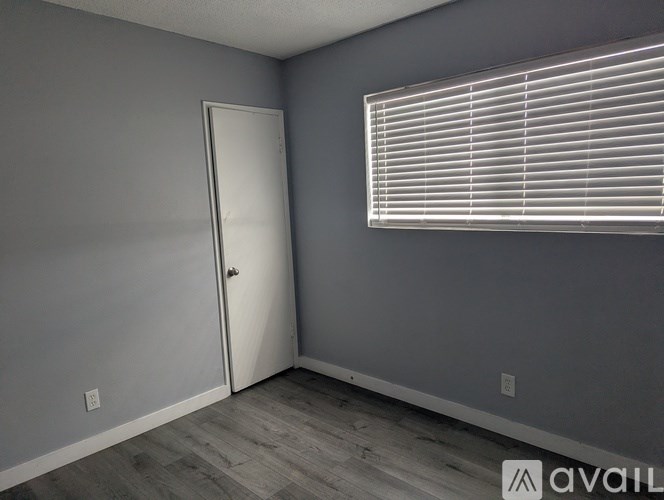 A room with a door and a window with blinds.