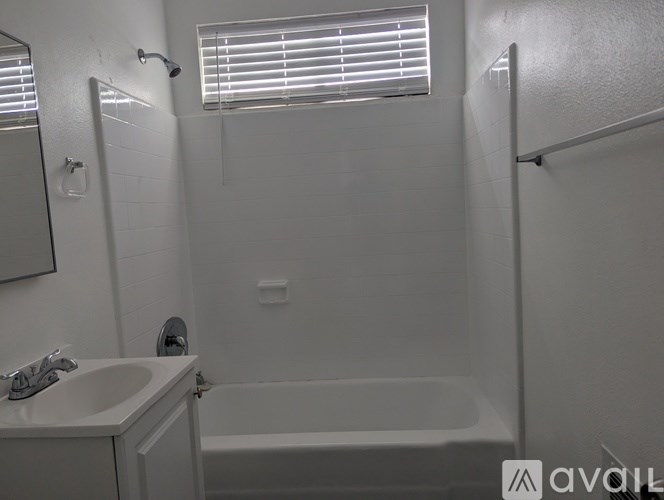 A white bathroom with a sink, mirror, and bathtub.