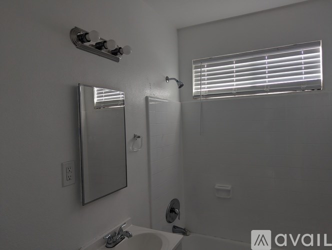 A bathroom with a sink, mirror, and shower.