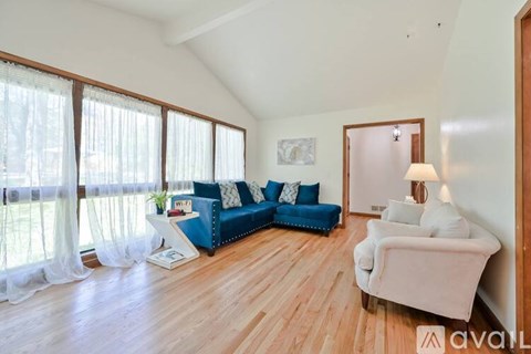 A living room with a blue couch and a white chair.