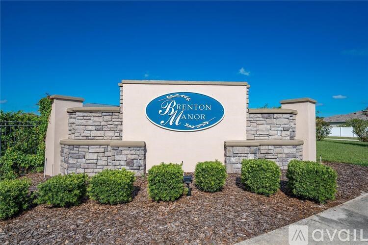 A sign for Brenton Manor is displayed in front of a clear blue sky.
