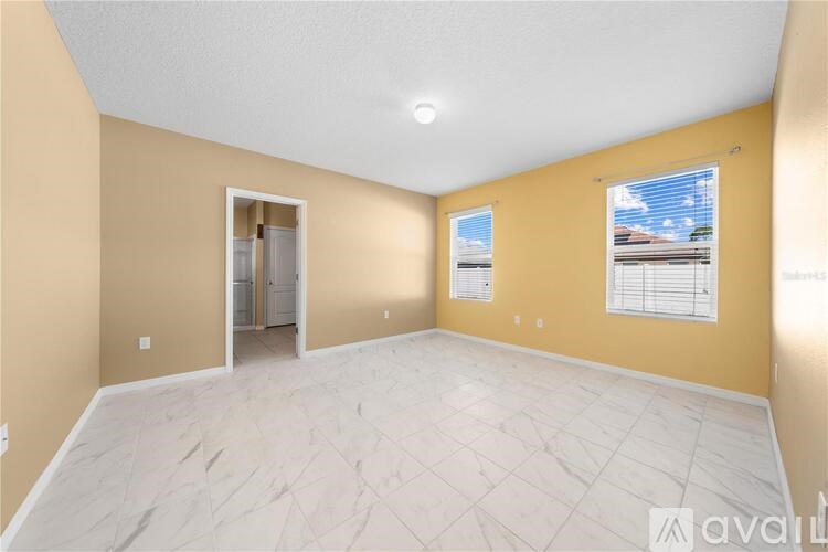 A spacious room with a marble floor and a view of the sky through the window.