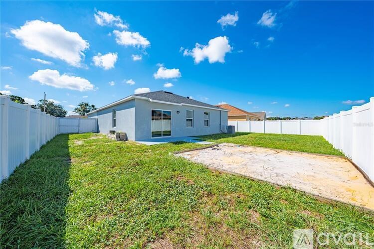 A white house with a grey roof is surrounded by a white fence.