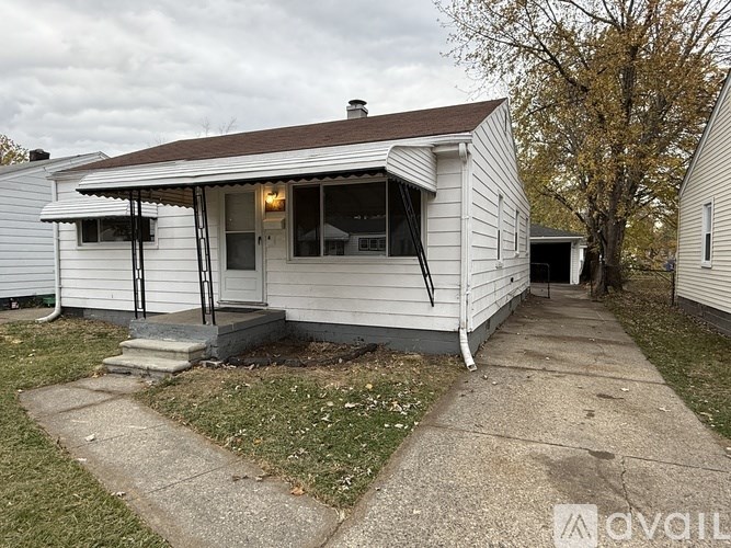 A white house with a brown roof and a porch.