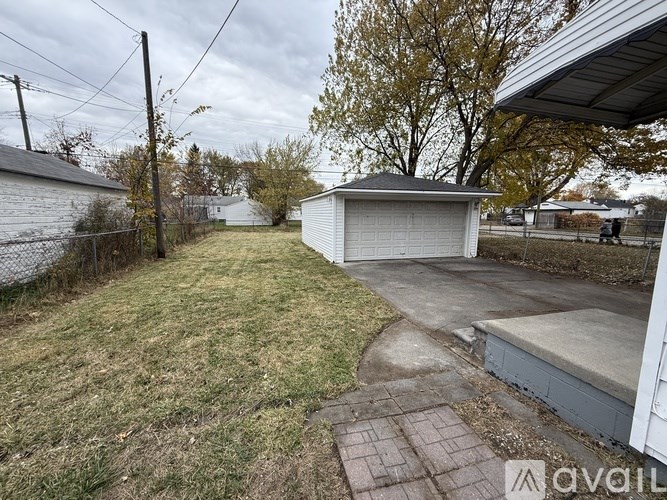 A backyard with a white garage and a concrete patio.