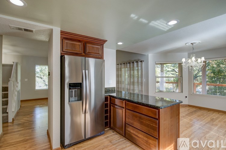 A modern kitchen with a stainless steel refrigerator and wooden cabinets.