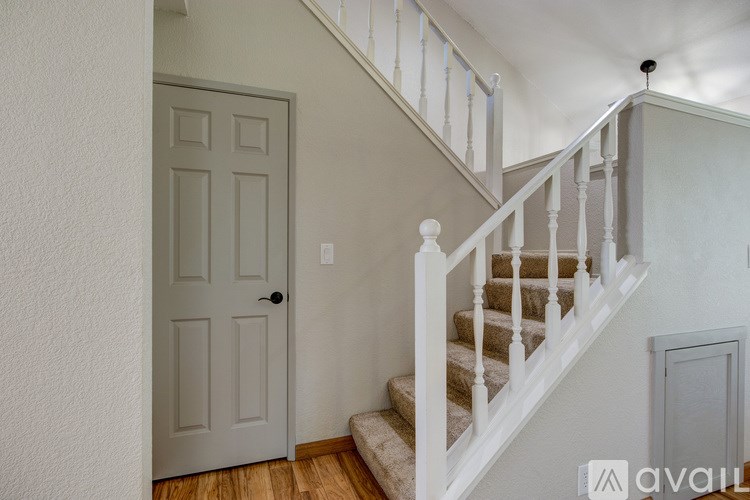 A white staircase with a white railing and a white door.