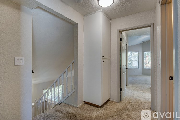 A hallway with a carpeted floor and white walls.