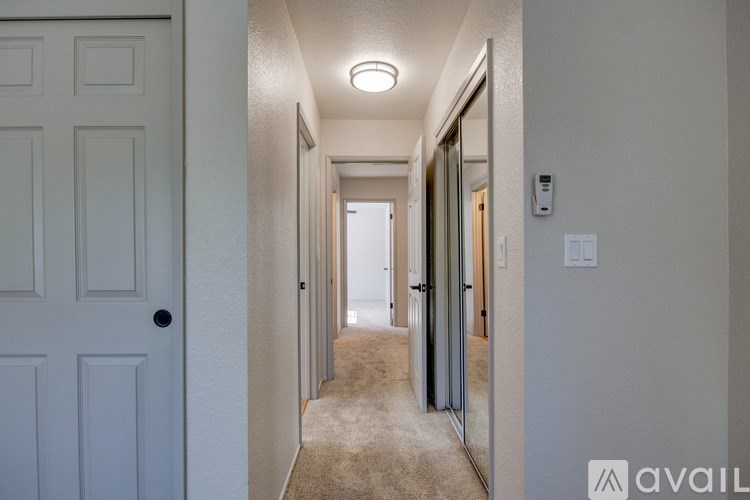 A hallway with a carpeted floor and white walls.