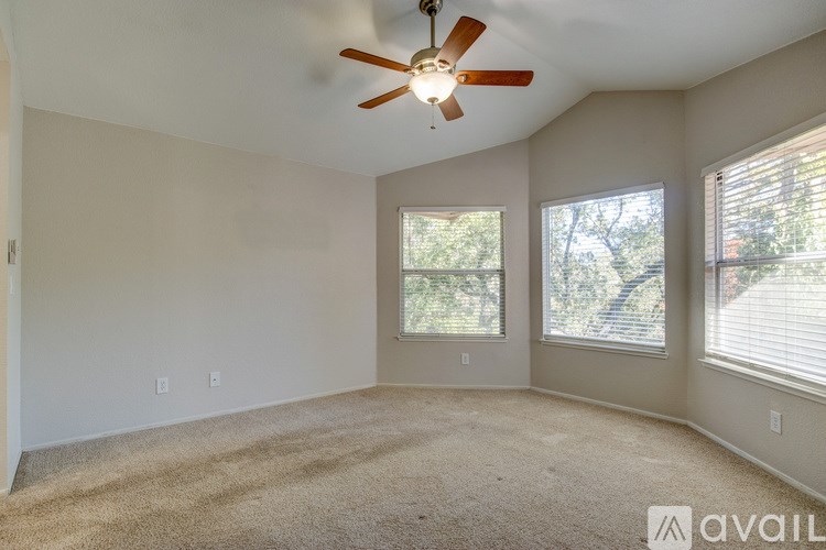 A room with a ceiling fan and two windows.