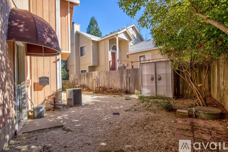 A gravel backyard with a fence and a tree.
