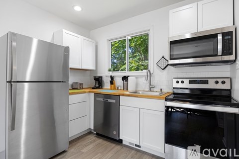 A modern kitchen with a stainless steel refrigerator and white cabinets.