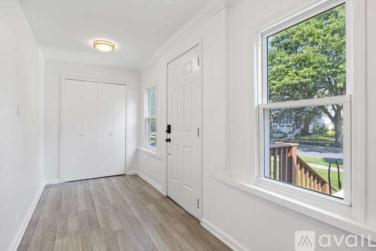 A room with white walls and a window showing a tree and a fence outside.