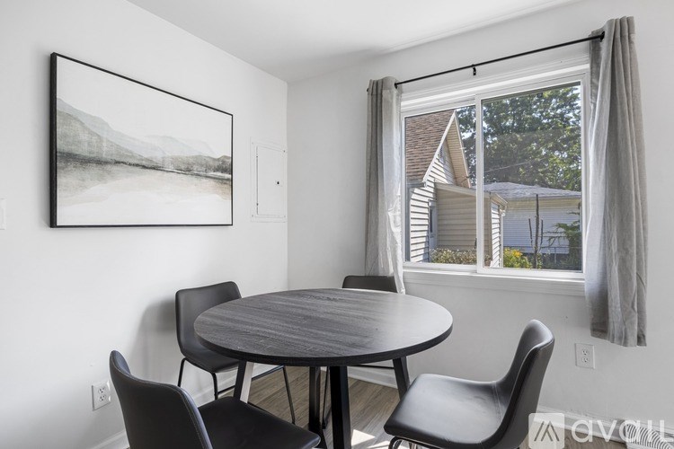 A dining room with a table and chairs and a picture on the wall.
